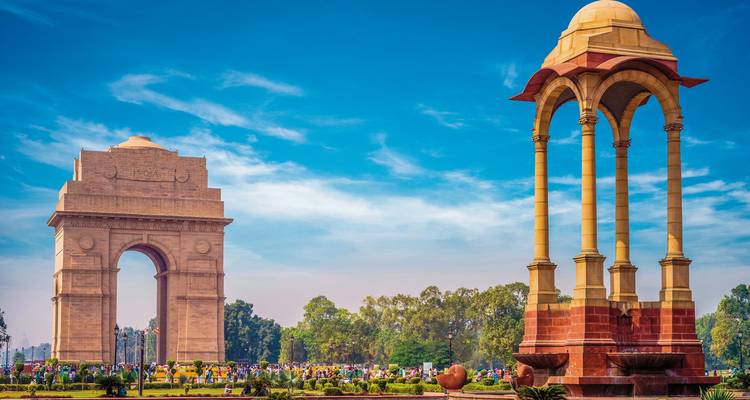 India Gate und ein Pavillon mit Menschen herum in einem Park.