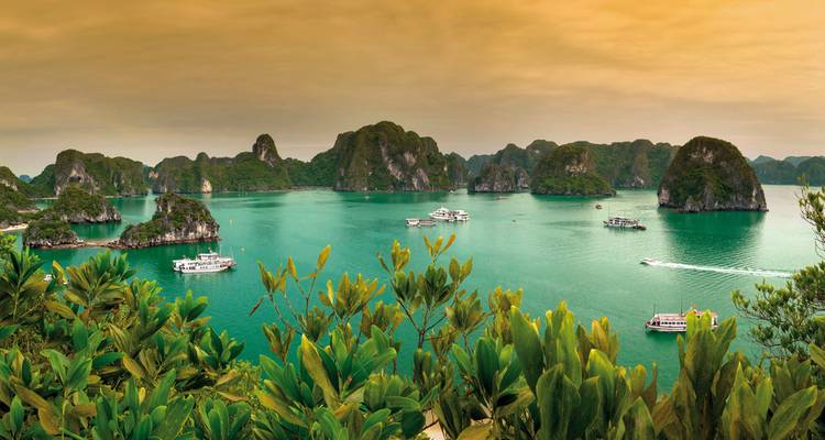 Halong Bay with boats and islands during sunset.