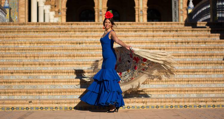 Woman in a flamenco dress posing on historic steps.