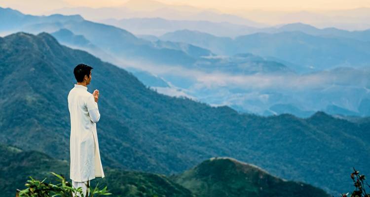Man standing on a mountain peak with view of misty mountains