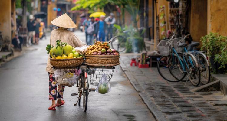 Street scene with a woman carrying goods on a bicycle