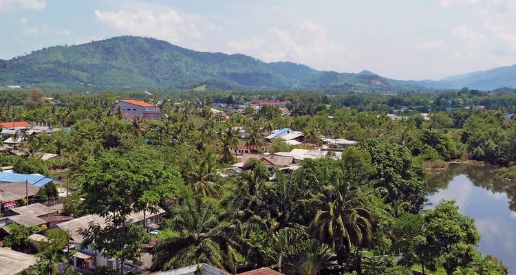 Vue d'un village entouré d'une végétation luxuriante et de collines.