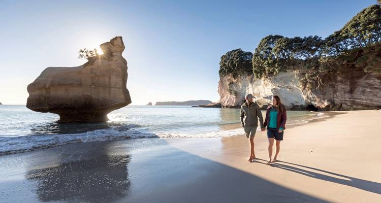 Stel dat langs een schilderachtig strand wandelt met rotsformaties.