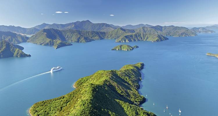 Aerial view of a ferry navigating between green islands.