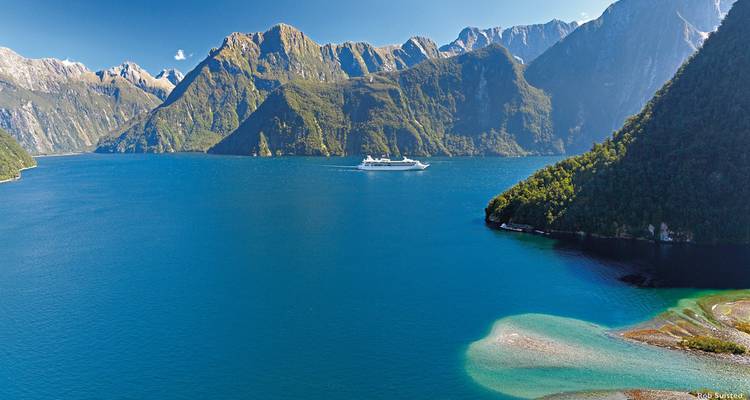 Cruise ship in a fjord surrounded by steep mountains.