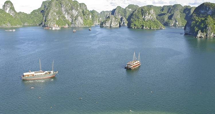 Bateaux naviguant dans les eaux calmes de la baie d'Halong avec des karsts calcaires.