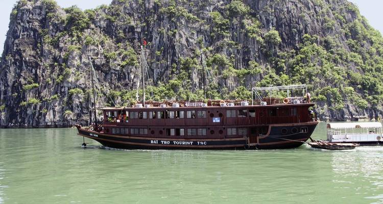 Un bateau touristique naviguant devant un karst calcaire dans la baie d'Halong.