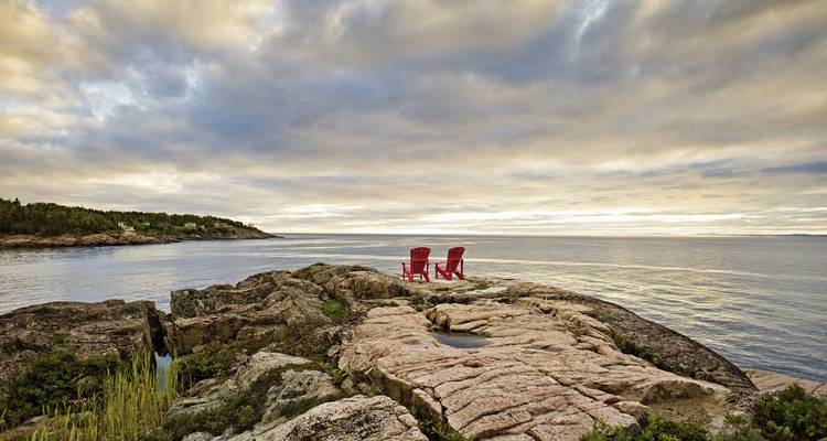 Deux chaises rouges sur un rivage rocheux surplombant l'océan.