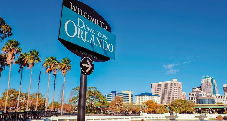 Panneau accueillant les visiteurs au centre-ville d'Orlando avec un paysage urbain en arrière-plan.