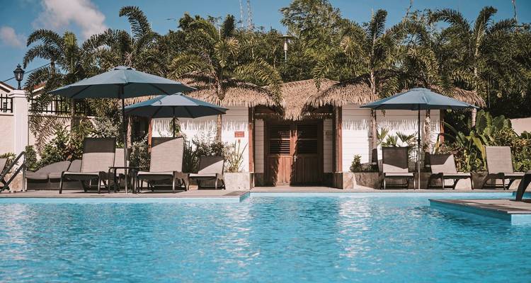 Poolblick mit tropischen Hütten und Palmen.