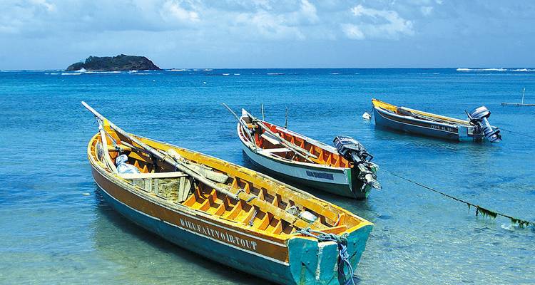 Boote, die in der Nähe des Ufers in klarem, blauem Wasser vor Anker liegen.
