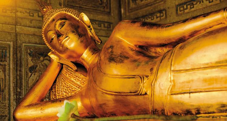 Gros plan d'une statue de Bouddha en or couchée.