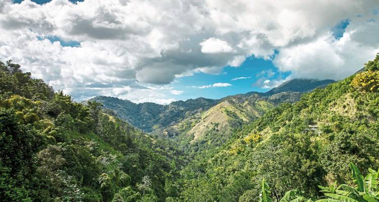Lush green mountains under a partly cloudy sky.