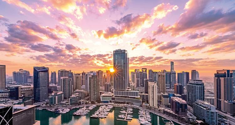 Vue du coucher de soleil sur Dubai Marina avec bateaux et gratte-ciel.