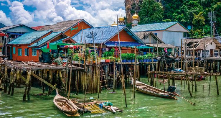 Colorful houses on stilts over the water with boats in the foreground.