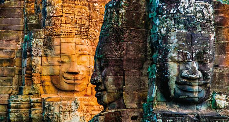 Gros plan de sculptures de visages sur un temple historique avec des expressions détaillées.