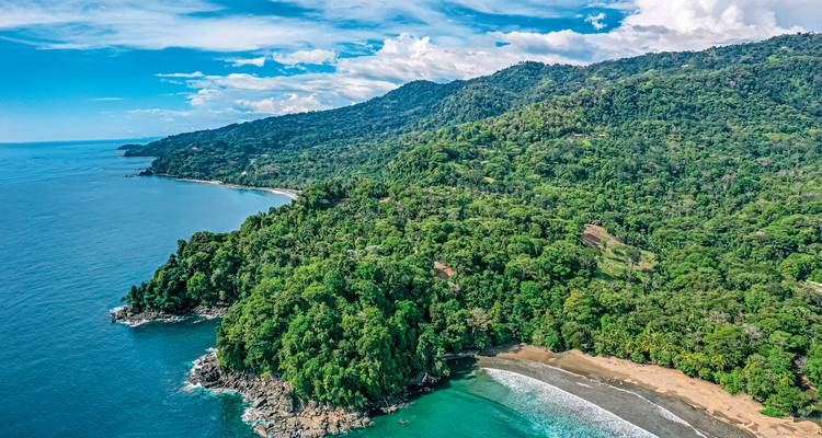 Aerial view of a tropical coastline with lush greenery and blue water.