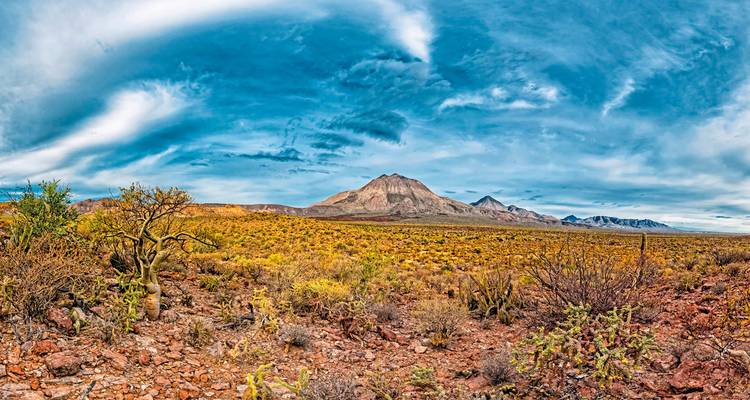 Desert landscape with mountains under a vast blue sky.
