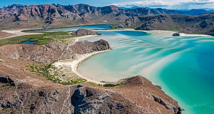 Beautiful bay with turquoise waters and sandy beaches surrounded by mountains.