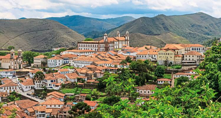 A view of a town with terracotta rooftops surrounded by hills.