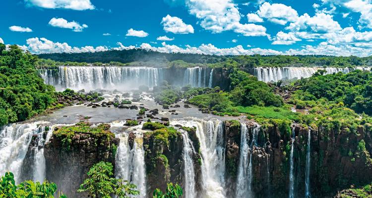 Panoramic view of waterfalls surrounded by lush greenery.