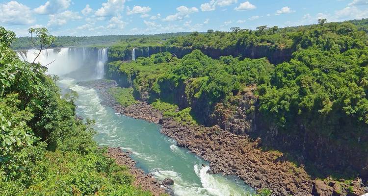 Panoramablick auf die Iguazu-Wasserfälle mit üppigem umliegendem Wald.