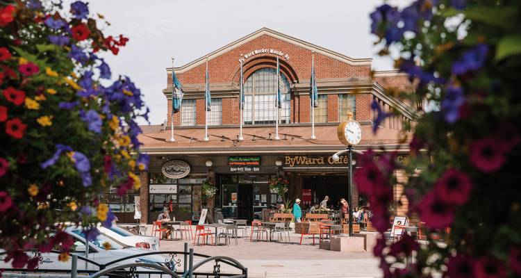 Outdoor cafe in a market square with people and flowers.