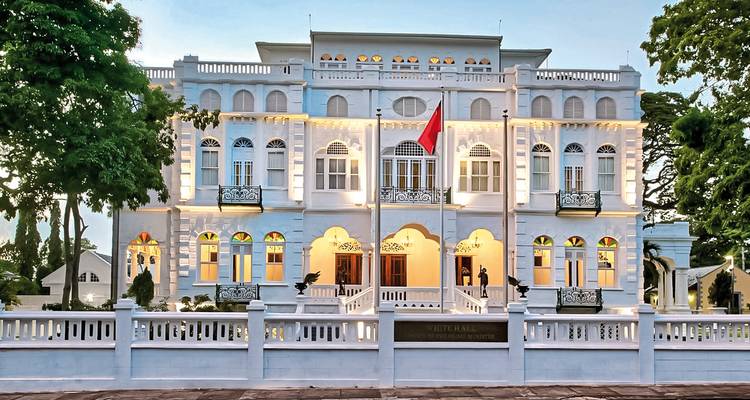 Elegant koloniaal gebouw met witte gevel en gemanicuurde gazon.