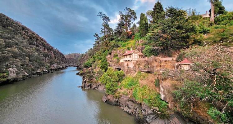Scenic river view with rocky cliffs and greenery.