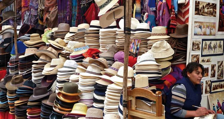 Marktstand mit einer großen Auswahl an Hüten und einem Verkäufer.