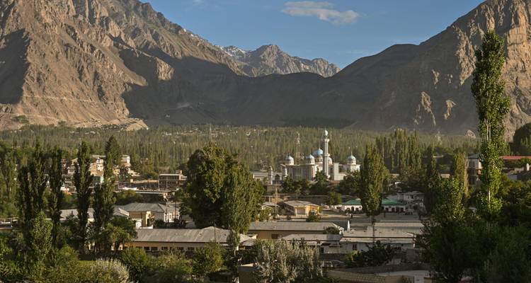 A valley town with a blue-domed mosque surrounded by towering barren mountains.
