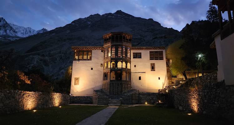 A lit heritage fort against a dusky mountain backdrop.