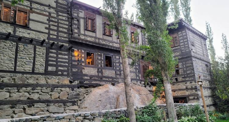 Rustic stone-and-wood traditional building set among tall poplar trees.