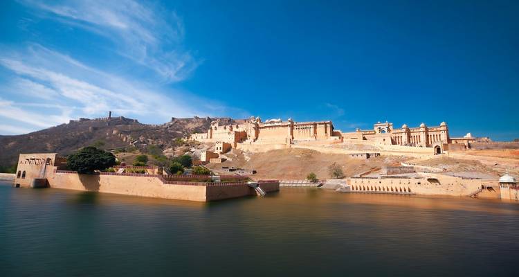 Le Fort d'Amber se reflétant dans le lac sous un ciel bleu clair.