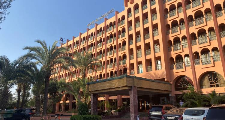 A hotel building with palm trees in the foreground.