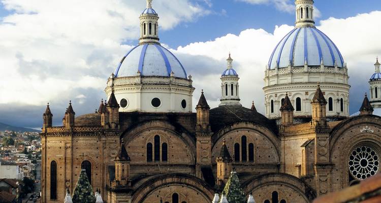 Domed blue-tiled roofs of Cuenca’s New Cathedral standing out against partly cloudy sky.