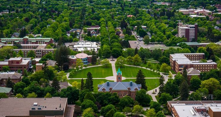 Vue aérienne d'un campus verdoyant avec un bâtiment central doté d'une tour d'horloge au milieu des quartiers de Missoula.