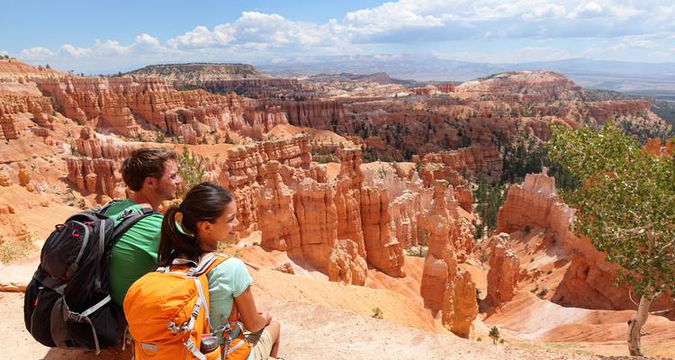 Wandelaars met rugzakken zitten op een kliprand en bewonderen Bryce Canyon's oranje hoodoos en uitgestrekte vergezichten.
