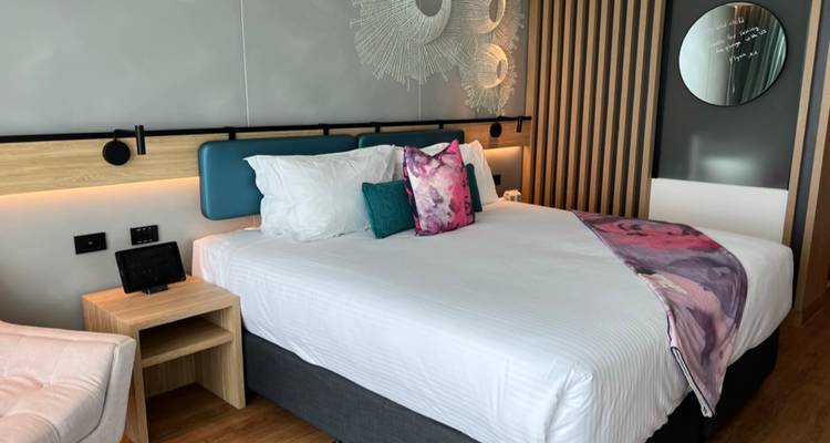 Intérieur d'une chambre d'hôtel moderne avec un lit fait et des éléments décoratifs.