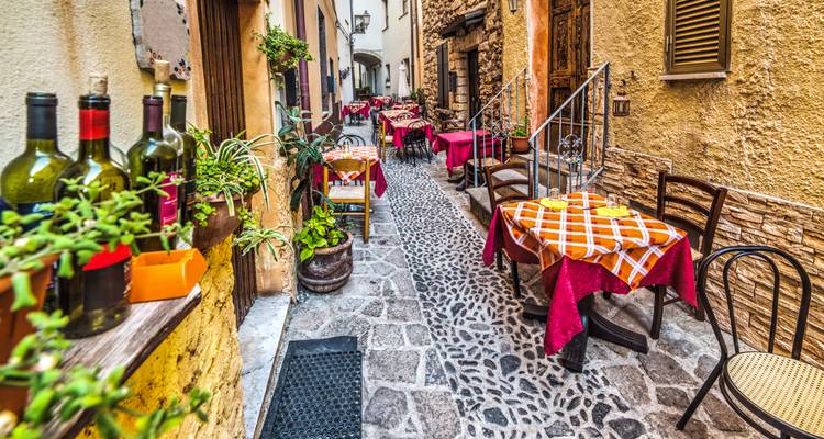 Charmante ruelle pavée avec terrasse de restaurant.
