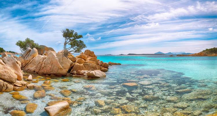 Côte rocheuse avec des eaux turquoise sous un ciel ensoleillé.