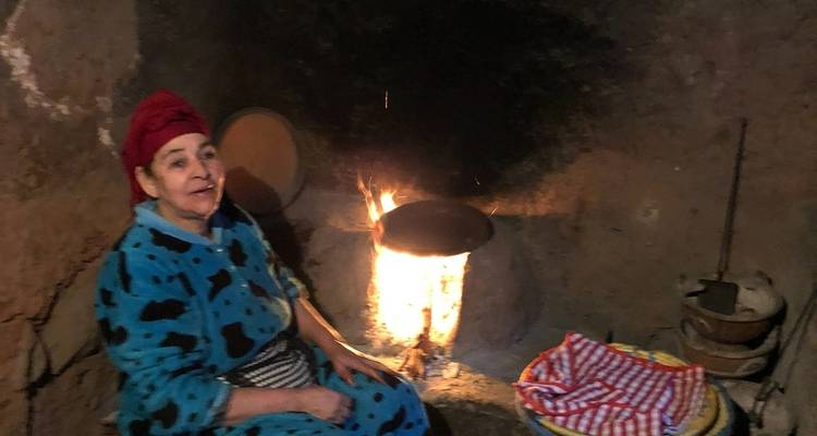 Frau sitzt an einem traditionellen Feuer und kocht.