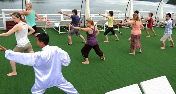 Grupo haciendo tai chi en la cubierta de un barco.