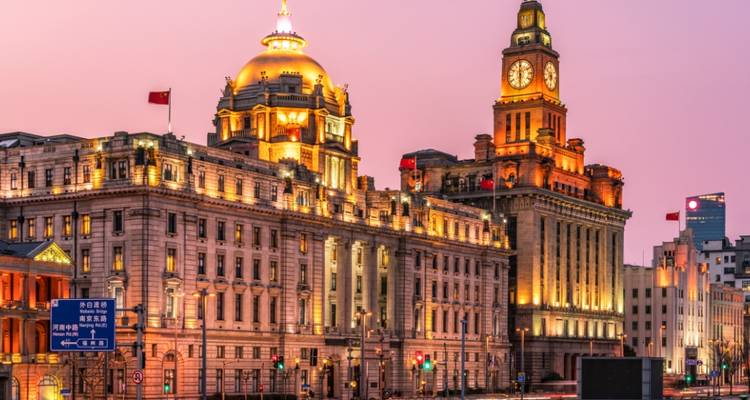 Historic buildings with domes and clock tower at sunset.