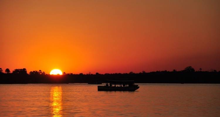 A boat on a river during a beautiful sunset.
