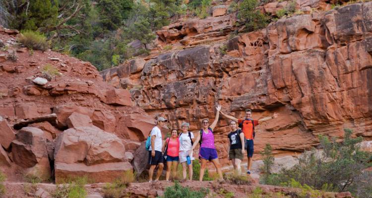 Groupe de randonneurs qui acclament dans un canyon de roches rouges.