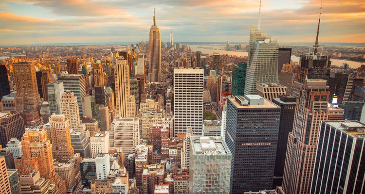 Dense skyline of Midtown Manhattan with Empire State Building at golden hour.