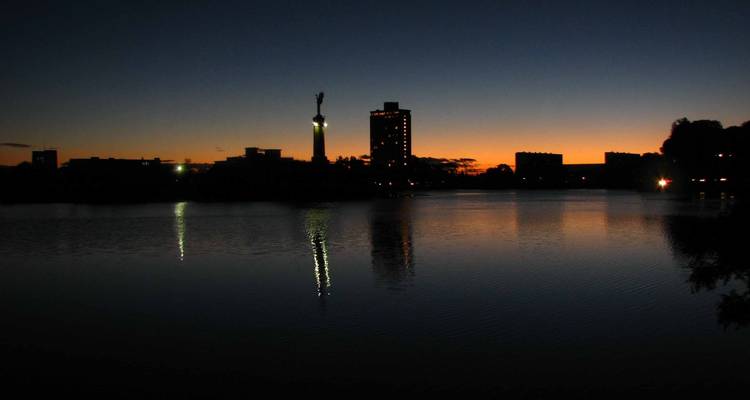 Building silhouettes against a twilight sky reflecting on water.