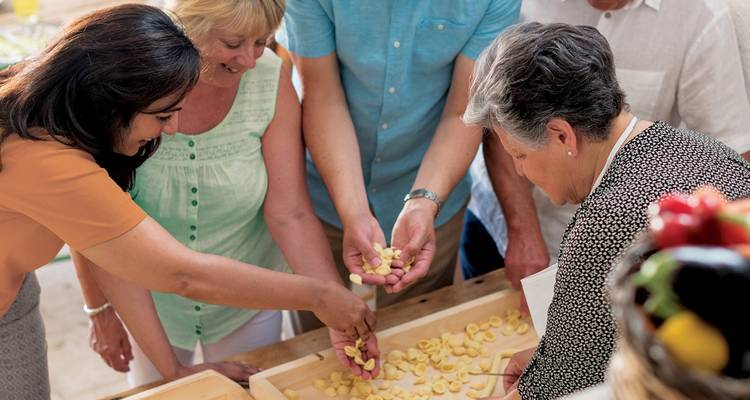 Des participants qui roulent de la pâte fraîche et façonnent des gnocchis ensemble pendant un cours de cuisine.