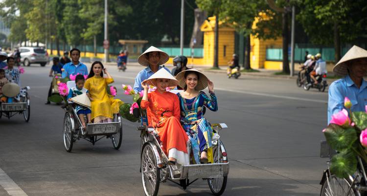 Toeristen in traditionele kledij die fietstaxi's berijden in een stadsstraat.